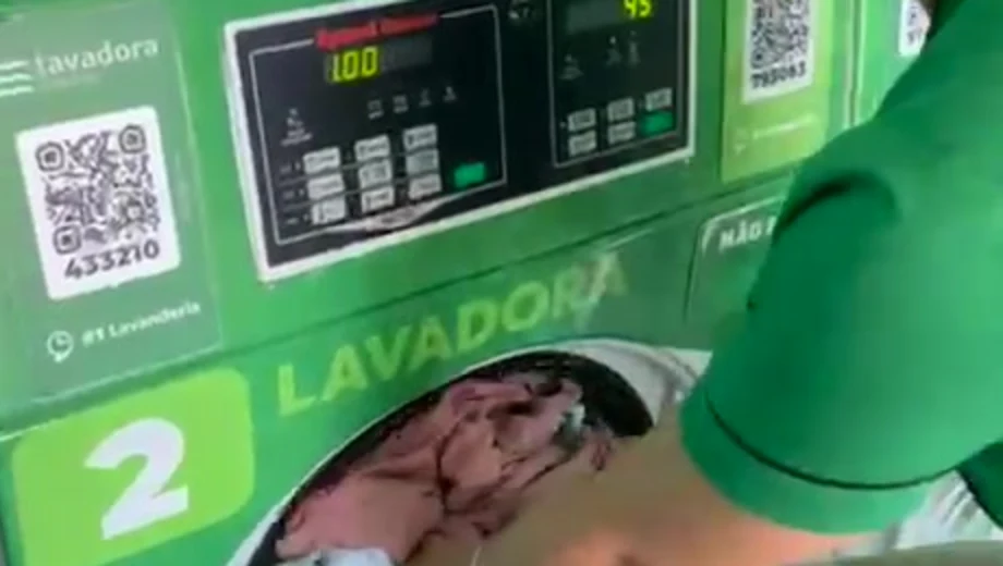 Mão colocando roupas na lavadora da #1 Lavanderia Express Cambolo